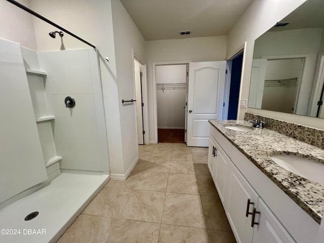 bathroom with walk in shower, vanity, and tile patterned flooring