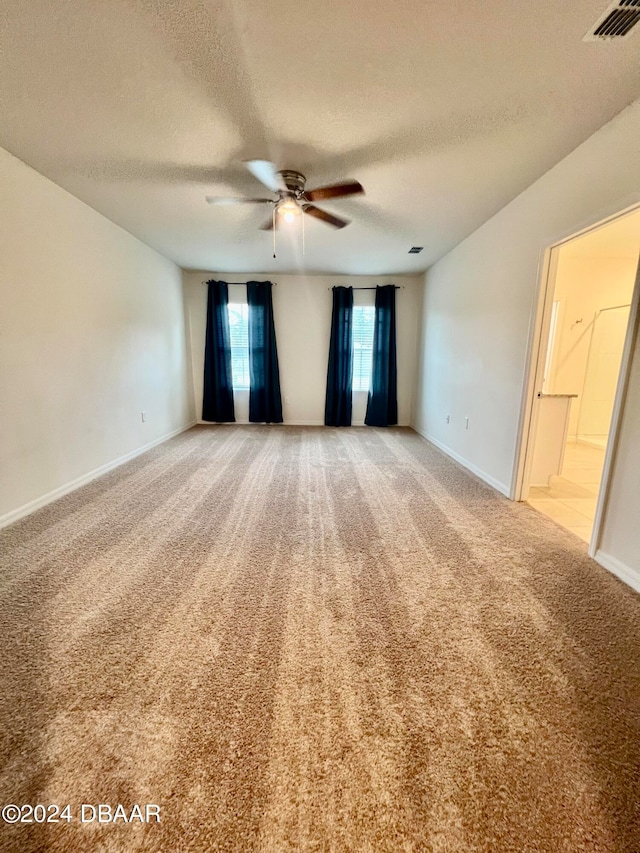 carpeted spare room with a textured ceiling and ceiling fan