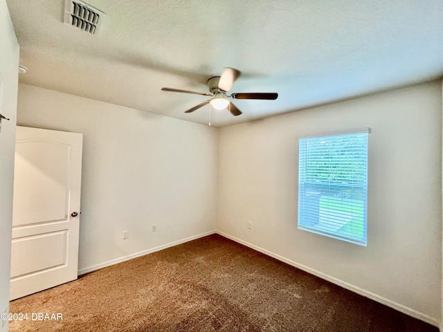 empty room featuring ceiling fan, a textured ceiling, and carpet flooring