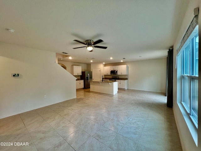 unfurnished living room featuring a wealth of natural light and ceiling fan