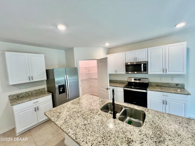 kitchen featuring light stone counters, appliances with stainless steel finishes, light tile patterned floors, sink, and white cabinets