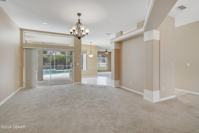 empty room with light carpet and ceiling fan with notable chandelier