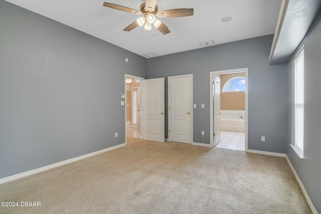 unfurnished bedroom featuring connected bathroom, light colored carpet, and ceiling fan