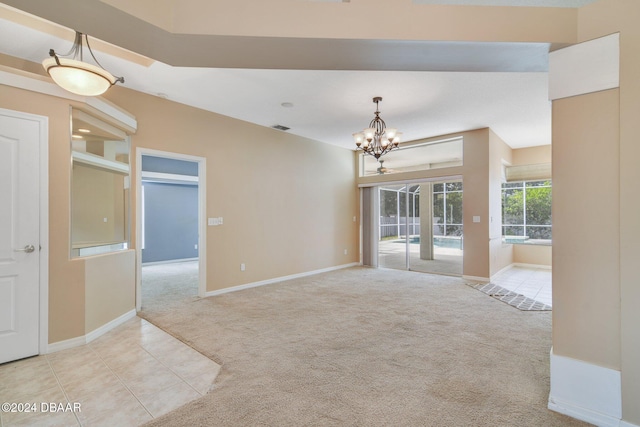 spare room with a notable chandelier and light colored carpet