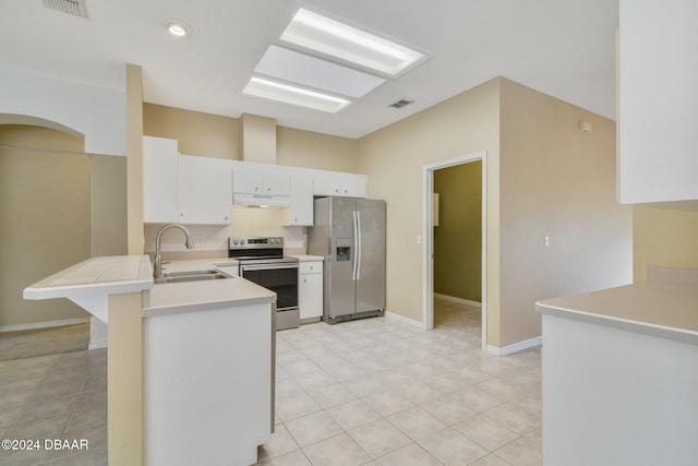 5976 Sawgrass Point Dr, Port Orange, FL 32128 - kitchen with appliances with stainless steel finishes, under cabinet range hood, a peninsula, arched walkways, and light countertops