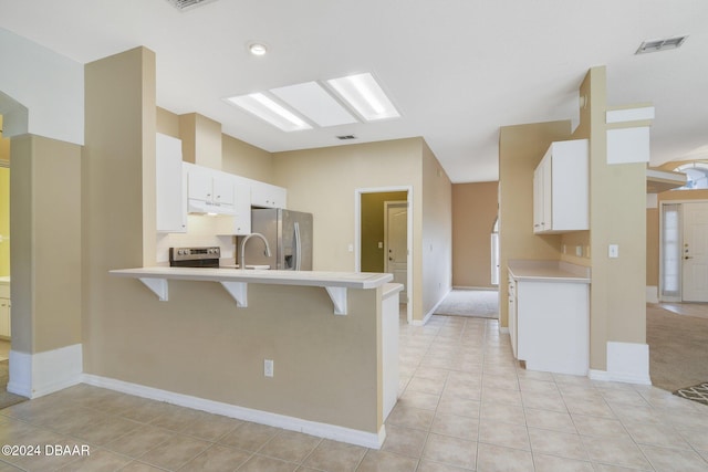 kitchen featuring a kitchen bar, appliances with stainless steel finishes, kitchen peninsula, and white cabinetry