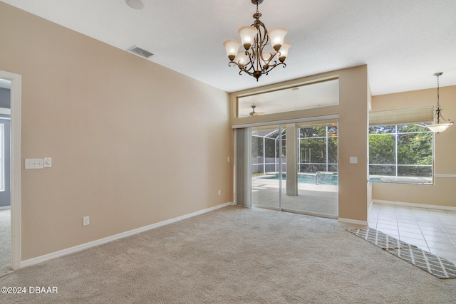 carpeted spare room featuring a notable chandelier