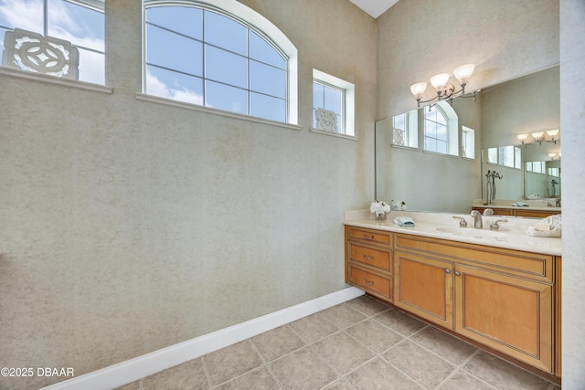 bathroom featuring baseboards, vanity, an inviting chandelier, and tile patterned floors