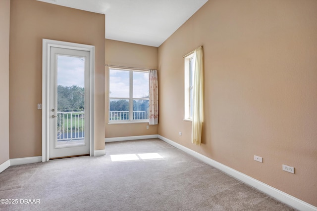 spare room featuring light carpet and baseboards