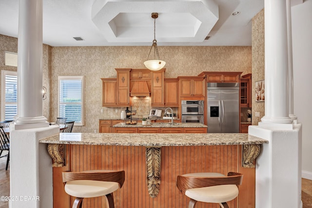 kitchen featuring stainless steel appliances, a breakfast bar, a peninsula, and ornate columns