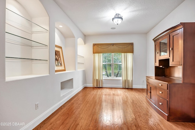 interior space with light wood-style flooring, baseboards, and a textured ceiling