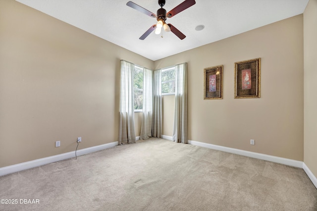 spare room featuring baseboards, a ceiling fan, and light colored carpet