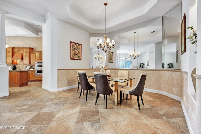 dining space with a raised ceiling, baseboards, and an inviting chandelier