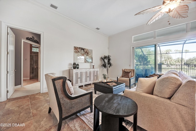 living room featuring a ceiling fan, visible vents, crown molding, and baseboards