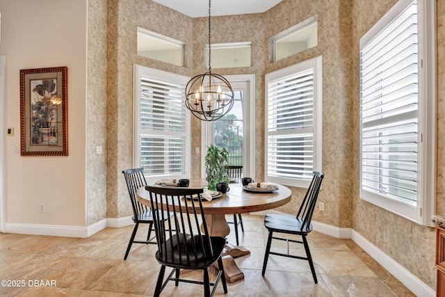 dining space featuring a high ceiling, wallpapered walls, baseboards, and an inviting chandelier