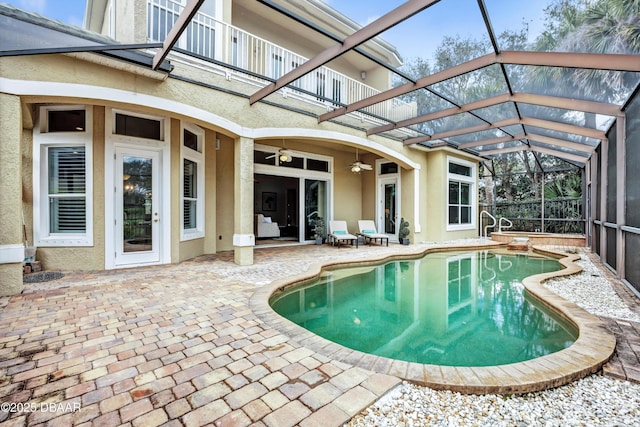 outdoor pool featuring glass enclosure, a patio area, and ceiling fan