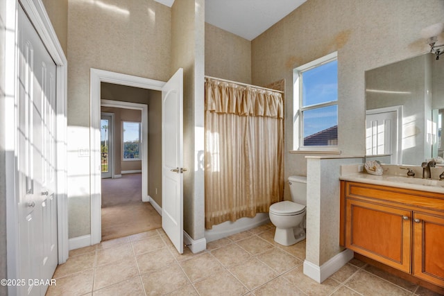 bathroom featuring tile patterned flooring, toilet, vanity, baseboards, and shower / bath combo with shower curtain