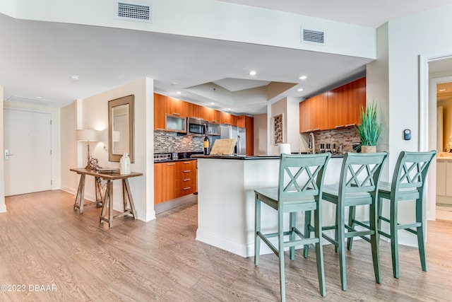 231 Riverside Dr Unit 1806, Holly Hill, FL 32117 - kitchen featuring appliances with stainless steel finishes, brown cabinetry, dark countertops, light wood-style floors, and recessed lighting