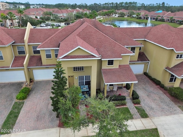 view of front facade with a residential view, roof with shingles, a water view, decorative driveway, and stucco siding