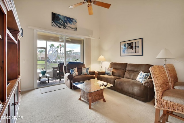 carpeted living area with a high ceiling and a ceiling fan