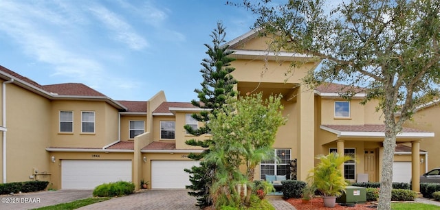 view of front facade featuring decorative driveway, an attached garage, and stucco siding