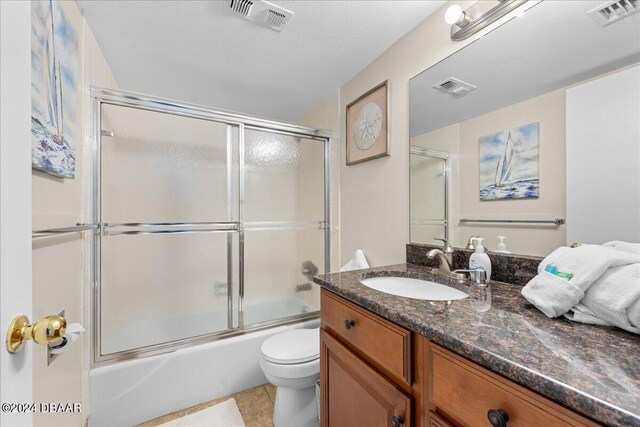 full bathroom featuring tile patterned flooring, vanity, combined bath / shower with glass door, and toilet