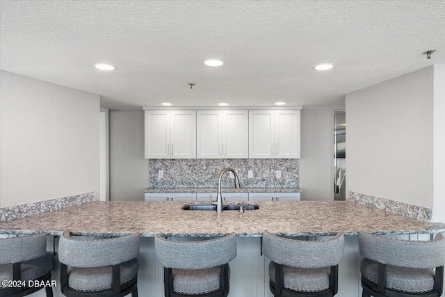 kitchen featuring white cabinets, a textured ceiling, sink, and tasteful backsplash