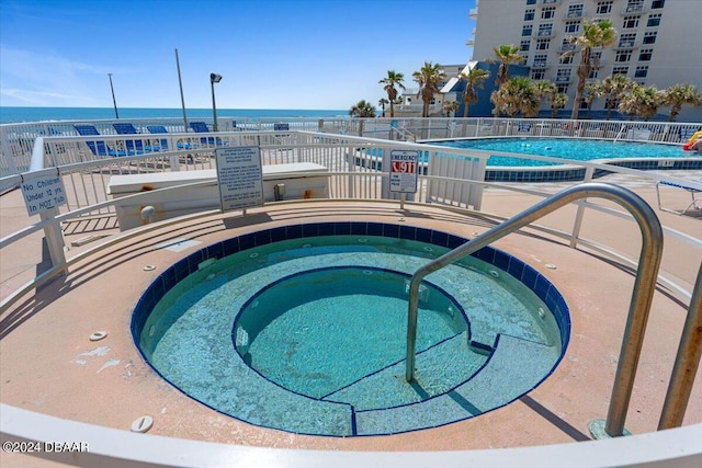 view of pool with a hot tub and a water view