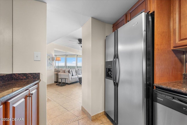 kitchen with stainless steel appliances, dark stone counters, ceiling fan, and light tile patterned floors