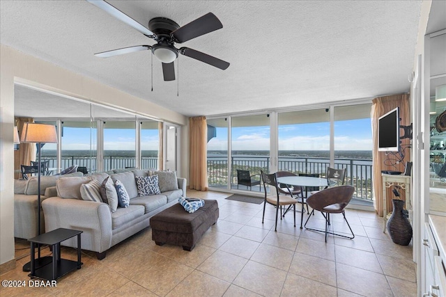 tiled living room featuring expansive windows, ceiling fan, and a textured ceiling