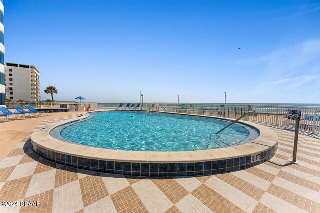 view of swimming pool with a water view and a patio