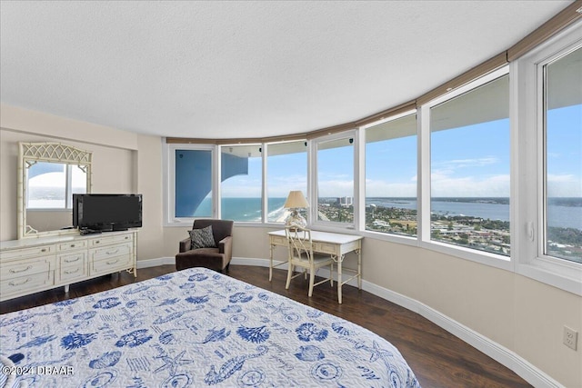 bedroom featuring a water view, a textured ceiling, and dark hardwood / wood-style floors