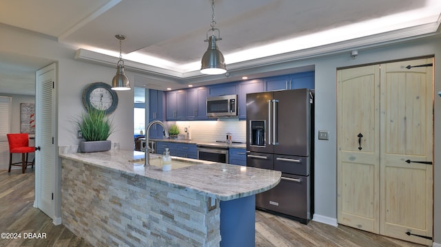 kitchen featuring stainless steel appliances, pendant lighting, hardwood / wood-style flooring, blue cabinets, and kitchen peninsula