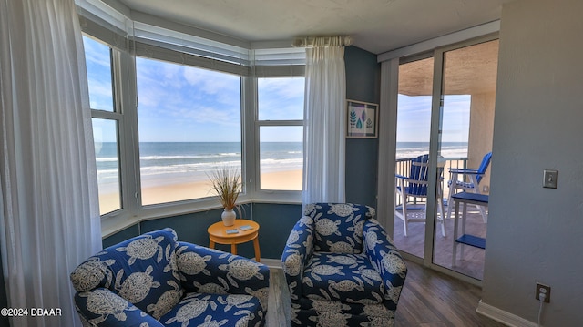 living area featuring dark hardwood / wood-style floors, a beach view, and a water view