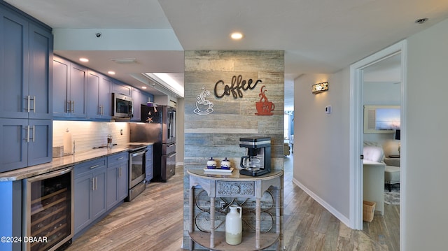 kitchen featuring stainless steel appliances, wine cooler, light hardwood / wood-style flooring, blue cabinets, and decorative backsplash