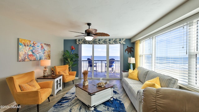 living room featuring hardwood / wood-style floors, a water view, and ceiling fan