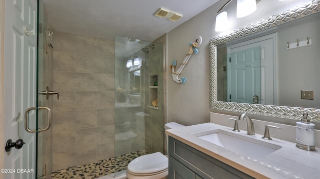 bathroom with toilet, vanity, and a shower with shower door