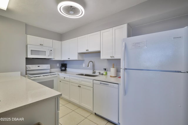 kitchen featuring white appliances, a sink, light tile patterned floors, white cabinets, and light stone counters