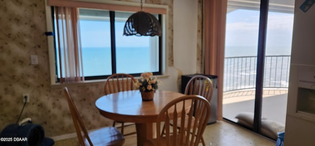 dining room with healthy amount of natural light, wallpapered walls, and a water view