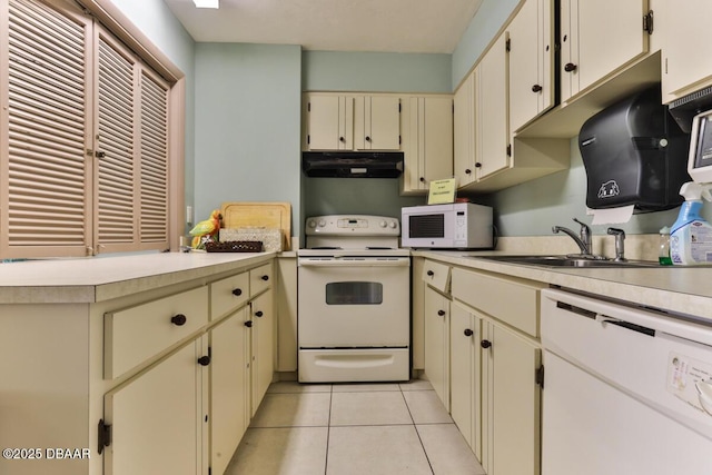 kitchen with white appliances, under cabinet range hood, cream cabinetry, and light countertops