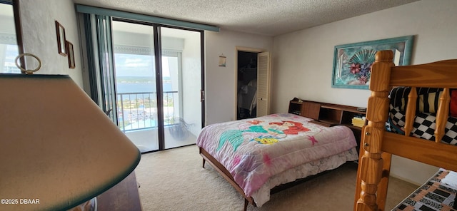 carpeted bedroom featuring access to exterior, a textured ceiling, and a water view