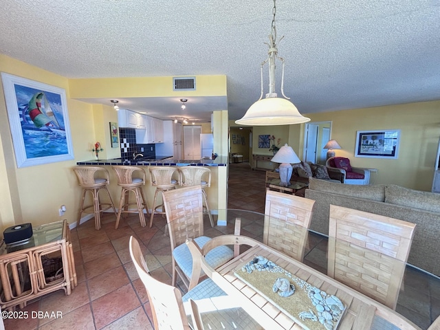 tiled dining space with a textured ceiling