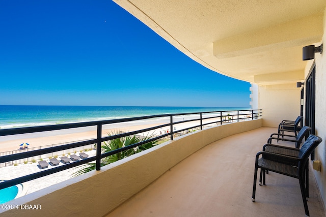 balcony with a water view and a view of the beach