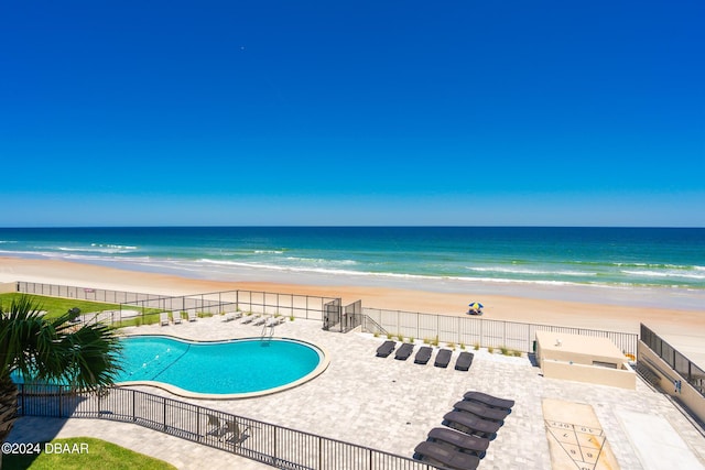 pool featuring a view of the beach, a water view, fence, and a patio