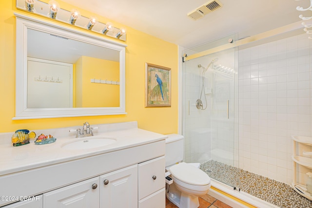 bathroom with tile patterned flooring, vanity, a shower with shower door, and toilet