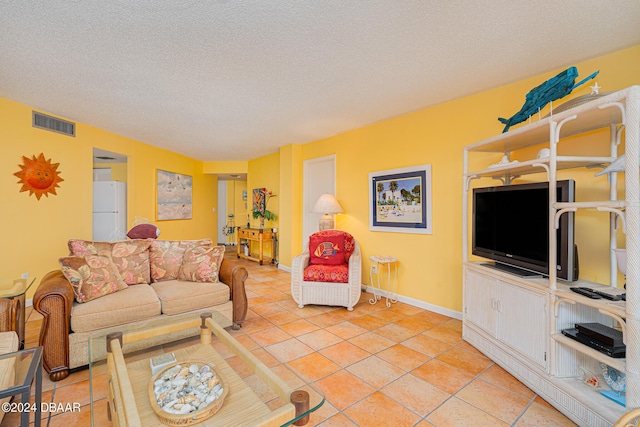 living room featuring a textured ceiling, light tile patterned floors, visible vents, and baseboards