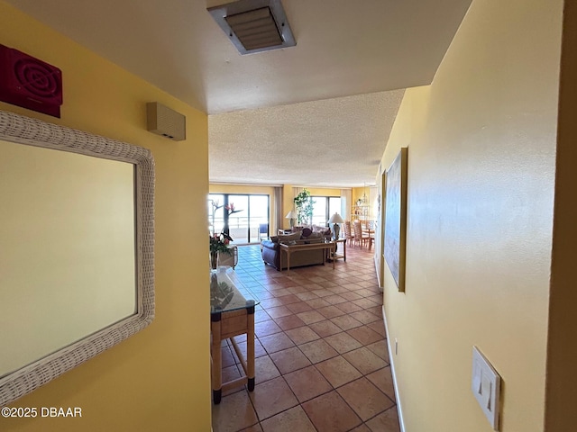 hallway with visible vents, a textured ceiling, and tile patterned floors