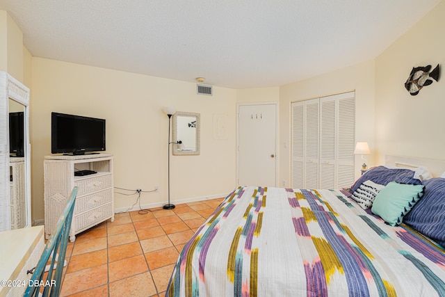 tiled bedroom featuring a textured ceiling and a closet