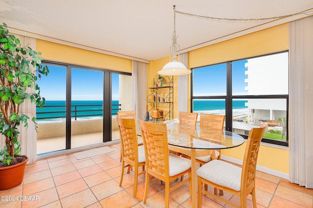 dining room with a water view, a beach view, and baseboards