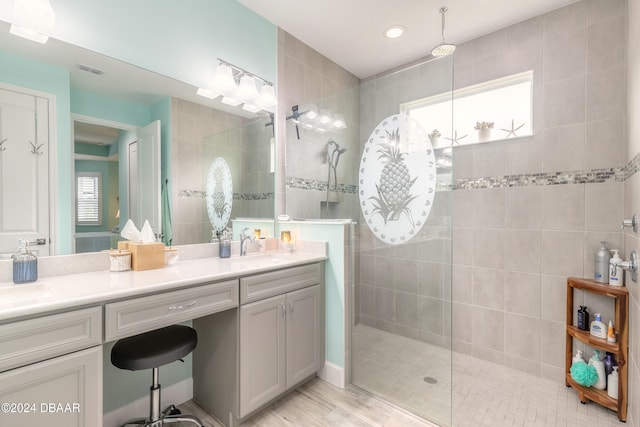 bathroom with vanity, hardwood / wood-style flooring, tiled shower, and plenty of natural light